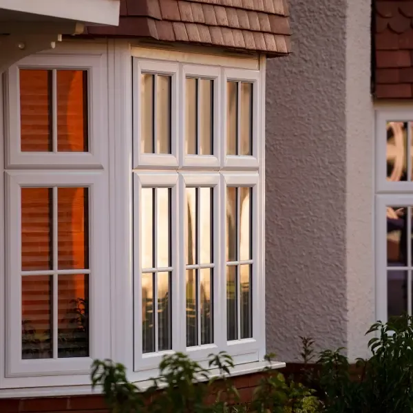 White bay window with glazing bars on a brick and rendered house