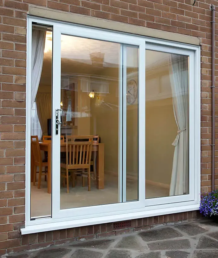 Large white sliding patio door in a brick wall, looking into a dining room