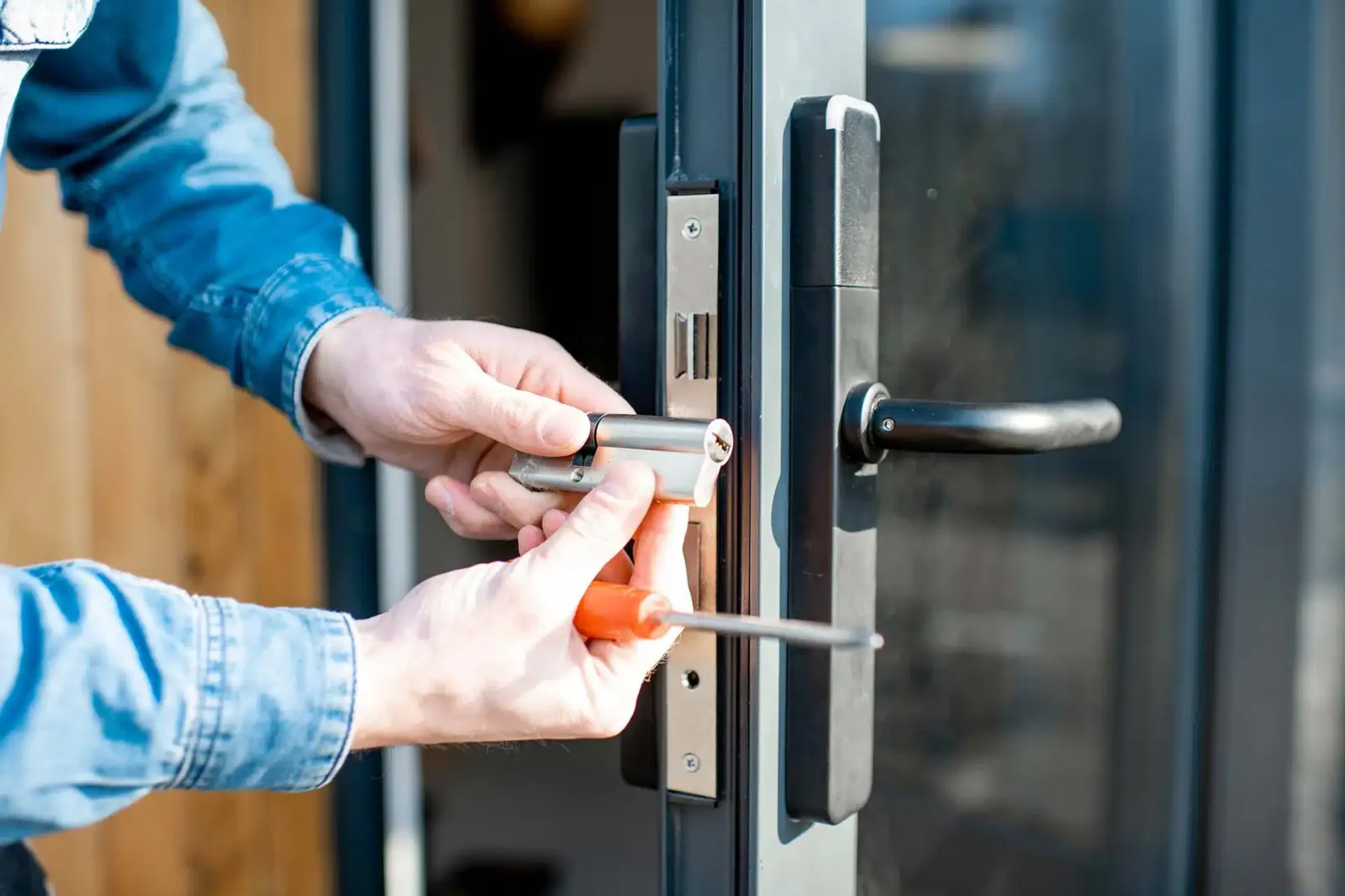 Hands working on the lock of a grey door