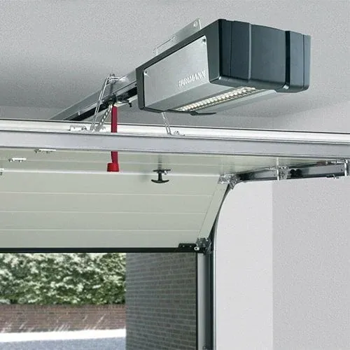 Garage door opener motor fitted to the ceiling above a white sectional door