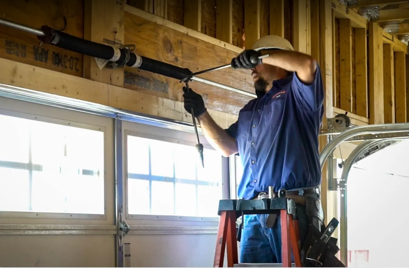 Fitter on a ladder working on a garage door mechanism