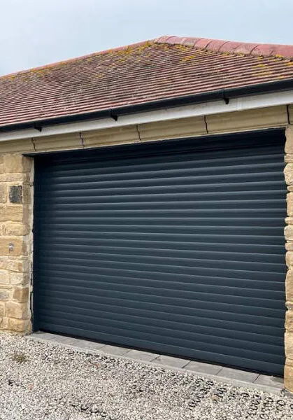 Dark roller garage door on a stone building with a tiled roof